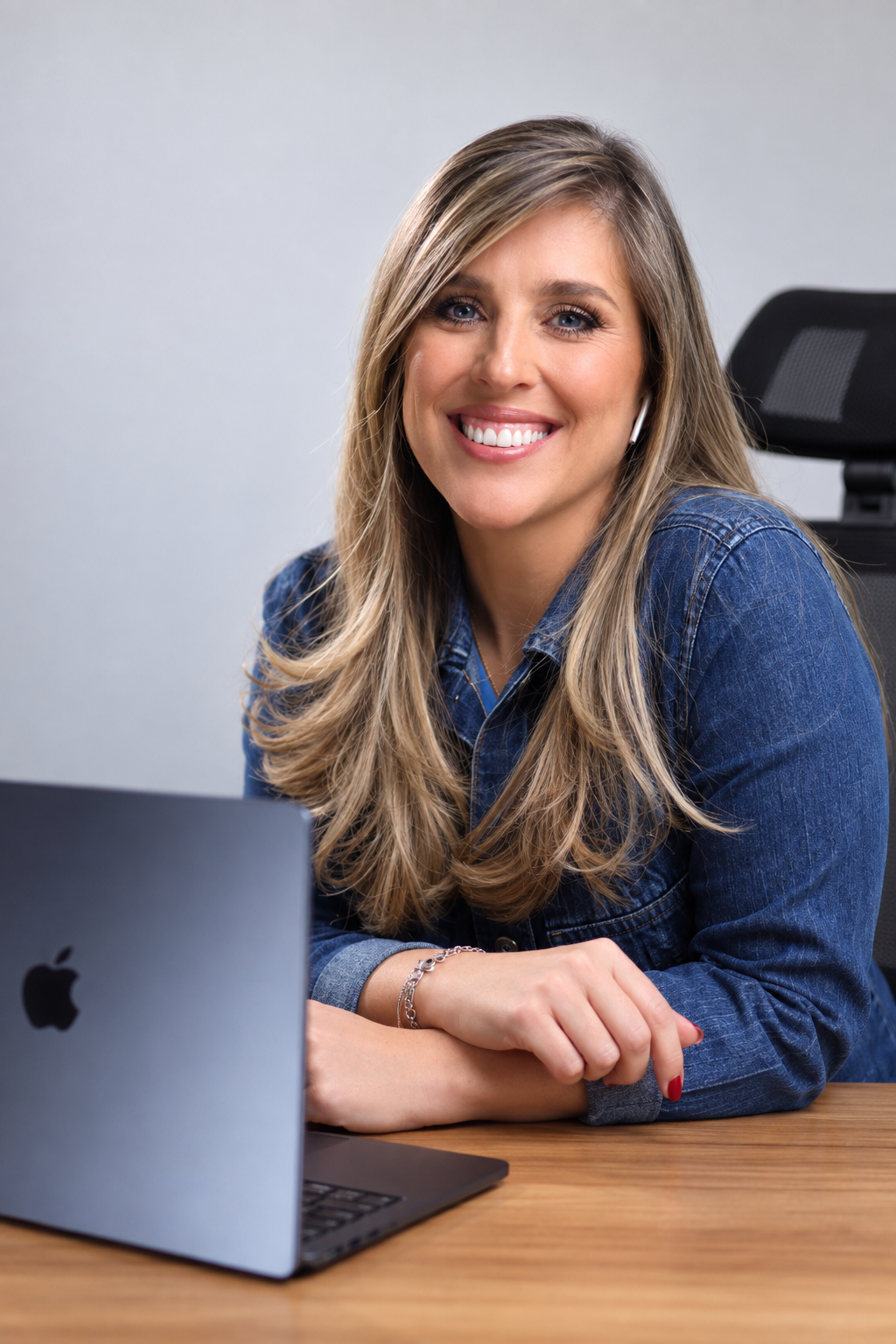 Maureen sorrindo, sentada à mesa com seu notebook.